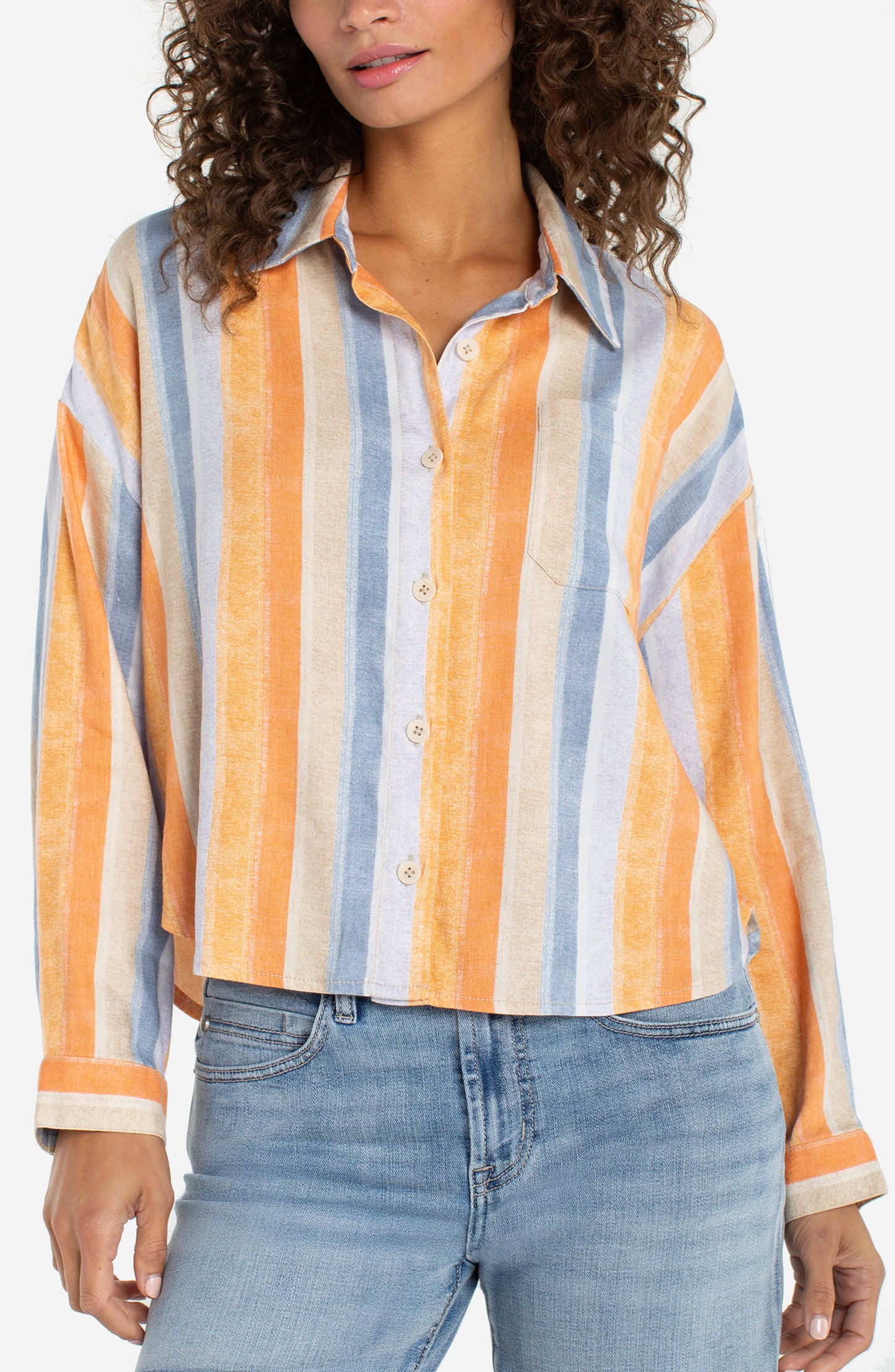 Woman wearing a colorful striped shirt and jeans on a white background