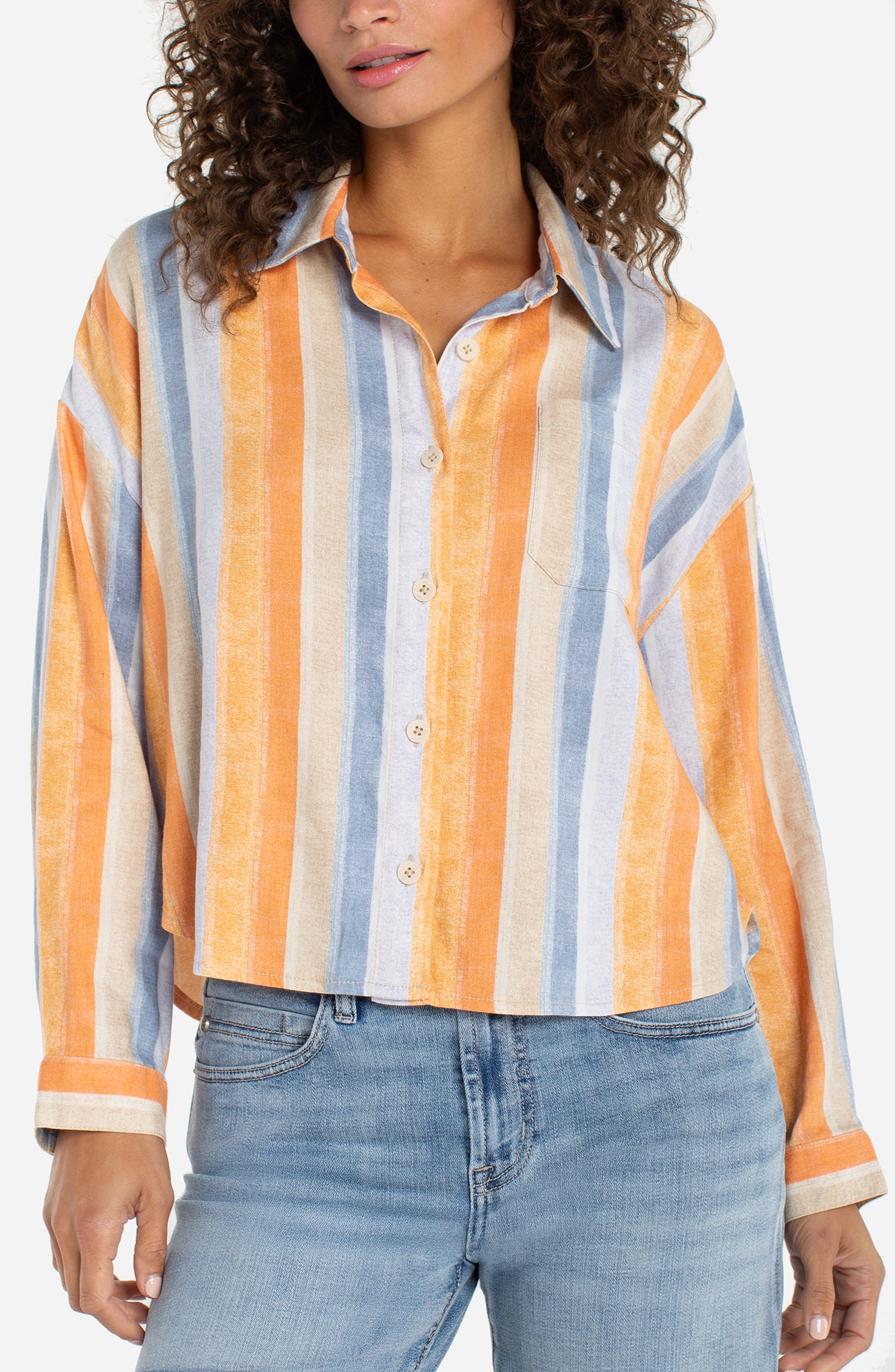 Woman wearing a colorful striped shirt and jeans on a white background